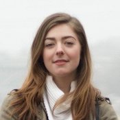 Headshot of Michelle Appleton, wearing a white shirt and a jacket, with a sea background.